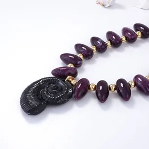 Vue détaillée du pendentif conque avec perles marbrées violettes et accents en métal doré
