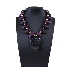 Détail des perles marbrées violettes et du grand pendentif coquillage noir sur présentoir