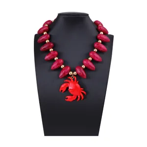 Collier de perles rouges marbrées avec un grand pendentif crabe sur un support