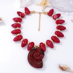 Détail macro de perles marbrées rouges et d'un grand pendentif en coquillage