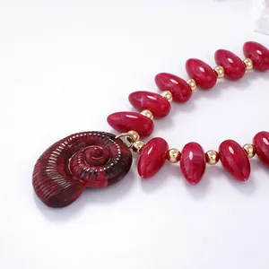 Détail macro de perles en résine rouge marbrée et grand pendentif nautile en spirale
