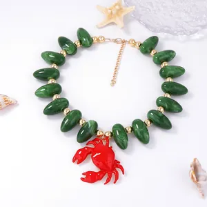 Détail du pendentif crabe rouge émaillé et perles olive marbrées sur collier marin
