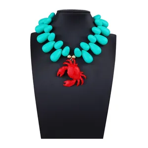 Dettaglio del ciondolo a forma di granchio rosso su collana di perline turchesi