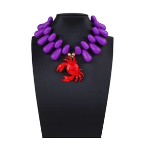 Dettaglio della collana con grandi perle viola a goccia e ciondolo a granchio rosso