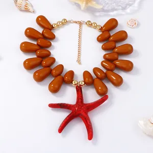 Detailed shot of large red starfish pendant with brown teardrop beads on white background