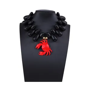 Dettaglio della collana con ciondolo a granchio rosso e grandi perle nere sul display
