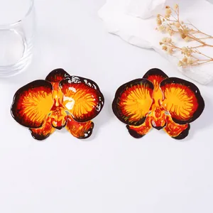 Exaggerated metal orchid earrings with red and yellow enamel glaze on white stone