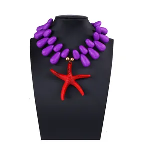 Detail of red starfish pendant and purple teardrop beads on a display mannequin