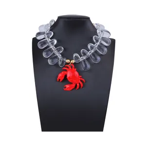 Dettaglio del ciondolo a granchio in smalto rosso e collana con perle acriliche trasparenti