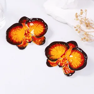 Detailed macro view of enamel orchid stud earrings with vibrant red-orange color gradient