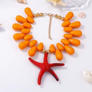 Detail of beaded necklace with orange waterdrop beads and a large red starfish pendant