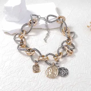 Détail du collier à chaîne bicolore avec des breloques vintage et pendentifs gravés
