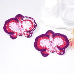 Detailed view of two orchid flower earrings with purple enamel coating and metallic finish