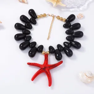 Macro detail of red starfish pendant on black bead necklace with marine style decor