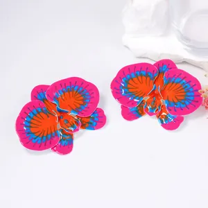 Macro detail of orchid floral earrings with vibrant pink, orange, and blue enamel finish