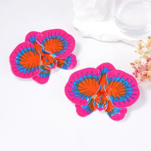 Detailed close-up of large enamel orchid earrings with pink, orange, and blue textures
