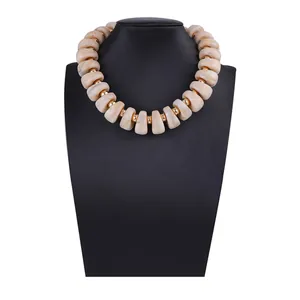 Détails de perles marbrées beige et d'entretoises dorées sur un collier à chaîne épaisse