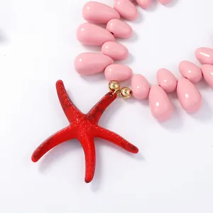 Macro detail of pink drop beads and vibrant red starfish pendant on beach necklace