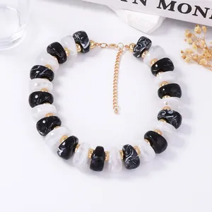 Détail de perles en résine marbrée rétro avec entretoises dorées et fermoir mousqueton