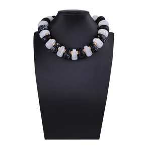 Détail de perles en résine marbrée et d'entretoises dorées sur ce collier choker