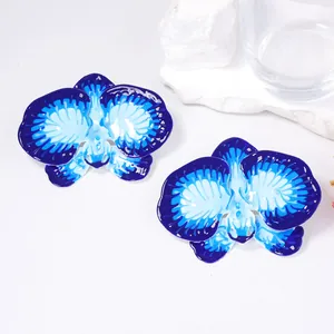 Detailed close-up of blue enamel orchid earrings with vibrant gradient petals