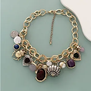 Detailed view of vintage gold chain necklace with beetle heart and shell charms