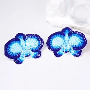 Macro detail of orchid flower earrings featuring blue gradient enamel and metal texture