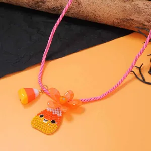 Dettaglio dei ciondoli Halloween candy corn e perline su collana in corda rosa