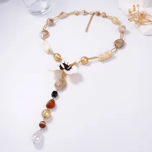 Dettaglio della collana a Y con fiore in smalto bianco e ciondolo perla barocca