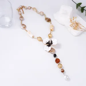 Dettaglio della collana a Y con ciondolo a fiore e catena di perline in resina