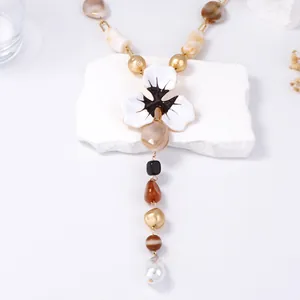 Dettaglio della collana a Y boho con fiore smaltato e pendente in perla barocca