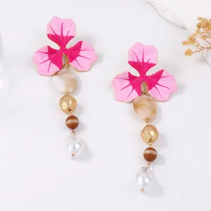 Dettaglio degli orecchini pendenti a fiore con smalto rosa e perle eleganti