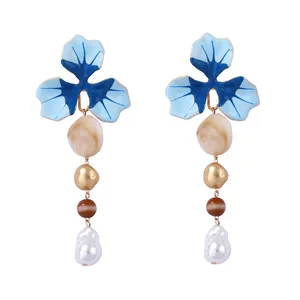 Dettaglio di orecchini a fiore con smalto blu e pendenti di perle barocche eleganti
