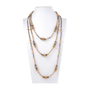 Detailed view of triple-layered CCB bead necklace in gold and gunmetal on white mannequin