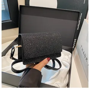 Detail der Glitzer Abendtasche in einer schwarzen Geschenkbox mit goldener Metallschnalle