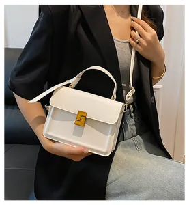 Detail of a white minimalist crossbody bag with elegant gold geometric metal lock