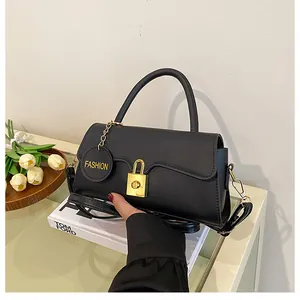 Close-up of black matte leather shoulder bag with golden lock and fashion tag detail