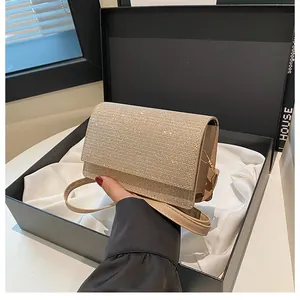 Detail der glitzernden Strasssteine auf der beigen Umhängetasche in einer Geschenkbox