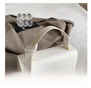 Detailed view of the comfortable white PU leather handle and gold hardware of the square bag