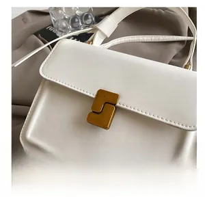 Detail showing the elegant S-shaped gold buckle and smooth cream leather texture