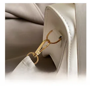 Detail of premium gold-toned metal spring hook and D-ring on white leather handbag