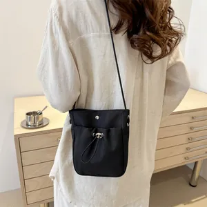 Minimalistische zwarte nylon mini crossbody telefoontas met trekkoord en metalen drukknoop