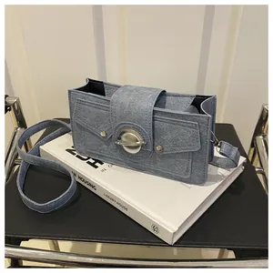 Détail du sac carré bleu clair en texture denim avec un grand fermoir en métal argenté
