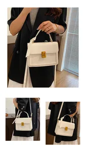 Detail of white leather handbag featuring a golden L-shaped twist lock and top handle