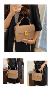Detail view of beige square crossbody bag featuring yellow geometric metal buckle and top handle