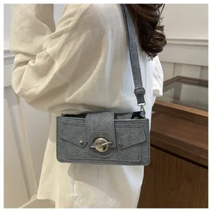 Vue détaillée du sac à bandoulière bleu gris texturé avec fermoir en métal sur modèle