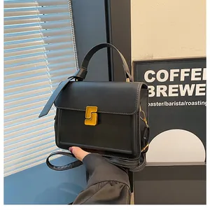 Detail of black leather handbag with square gold interlocking clasp and top handle
