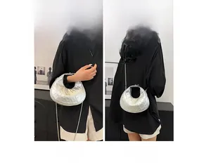 Gros plan du motif matelassé argenté et de la chaîne métallique du sac hobo en demi-lune