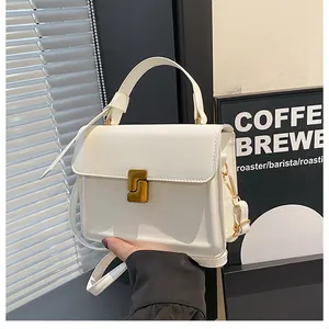 Detail of white leather square handbag with golden geometric clasp and top handle