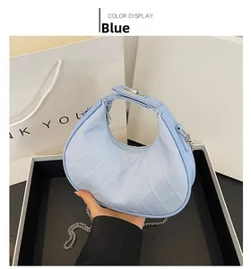 Détail du sac lune matelassé bleu clair avec chaîne argentée et fermoir rotatif métal